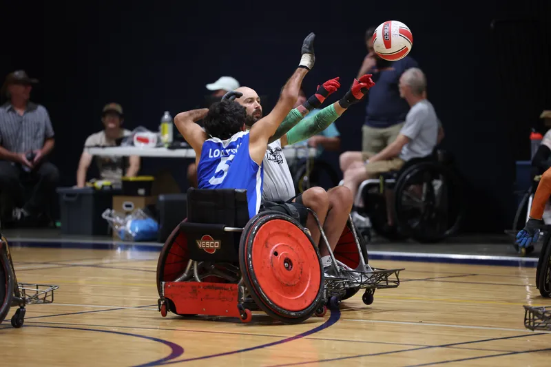 A defender stretches high to punch the ball loose over an opponent's chair