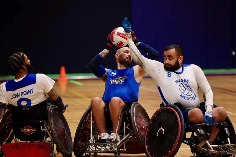 A grinning player flips the ball skyward while tangled with an opponent