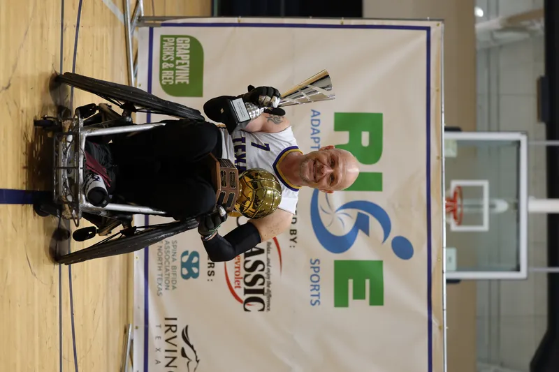 An athlete with taped forearms pops the ball up off his chair, eyes locked on it