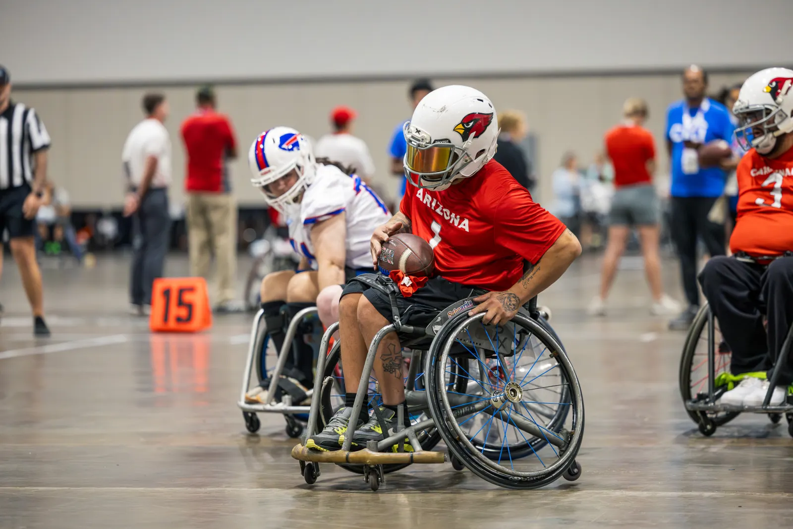 An Arizona Cardinals player in a red jersey cradles the football in his lap while a Bills opponent trails behind.