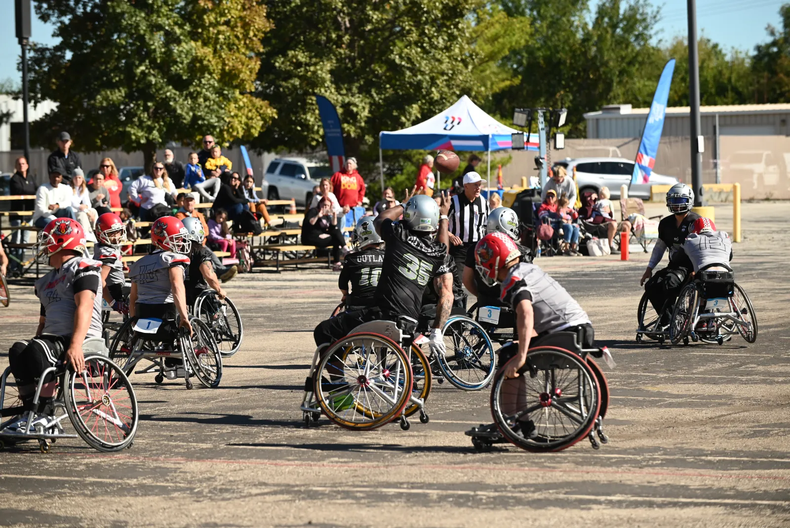 An Irving Outlaws player in a black number 35 jersey releases a pass that hangs in the air, surrounded by teammate number 10 and gray-jersey Kansas City players in red helmets.