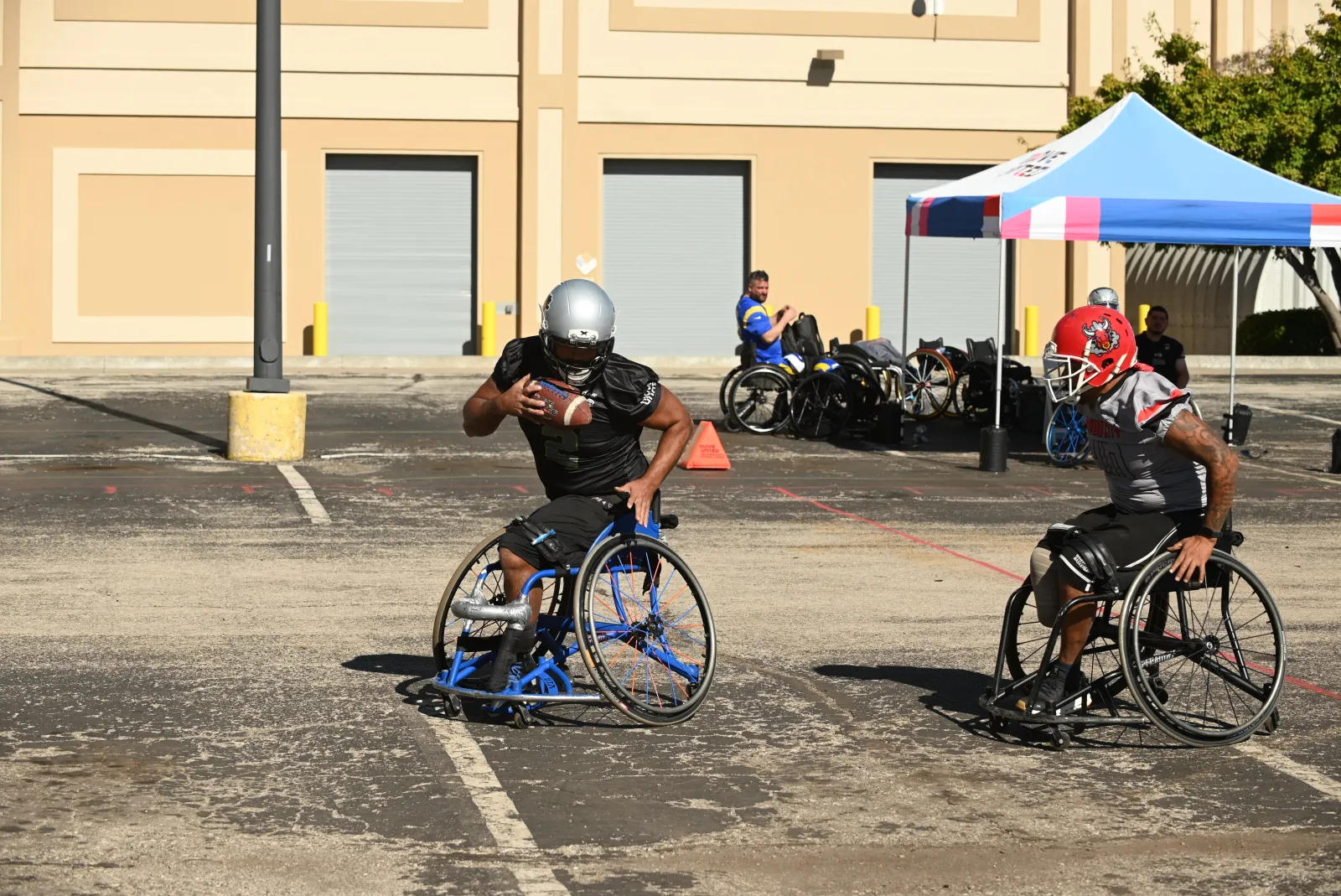 An Irving Outlaws player in a black jersey and silver helmet tucks the football and drives forward past a gray-jersey Kansas City defender in a red helmet on the open lot.
