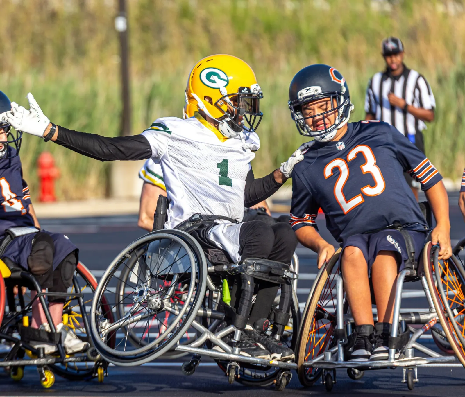 A Packers player in a gold helmet and a Bears number 23 player grab at each other as their chairs collide.