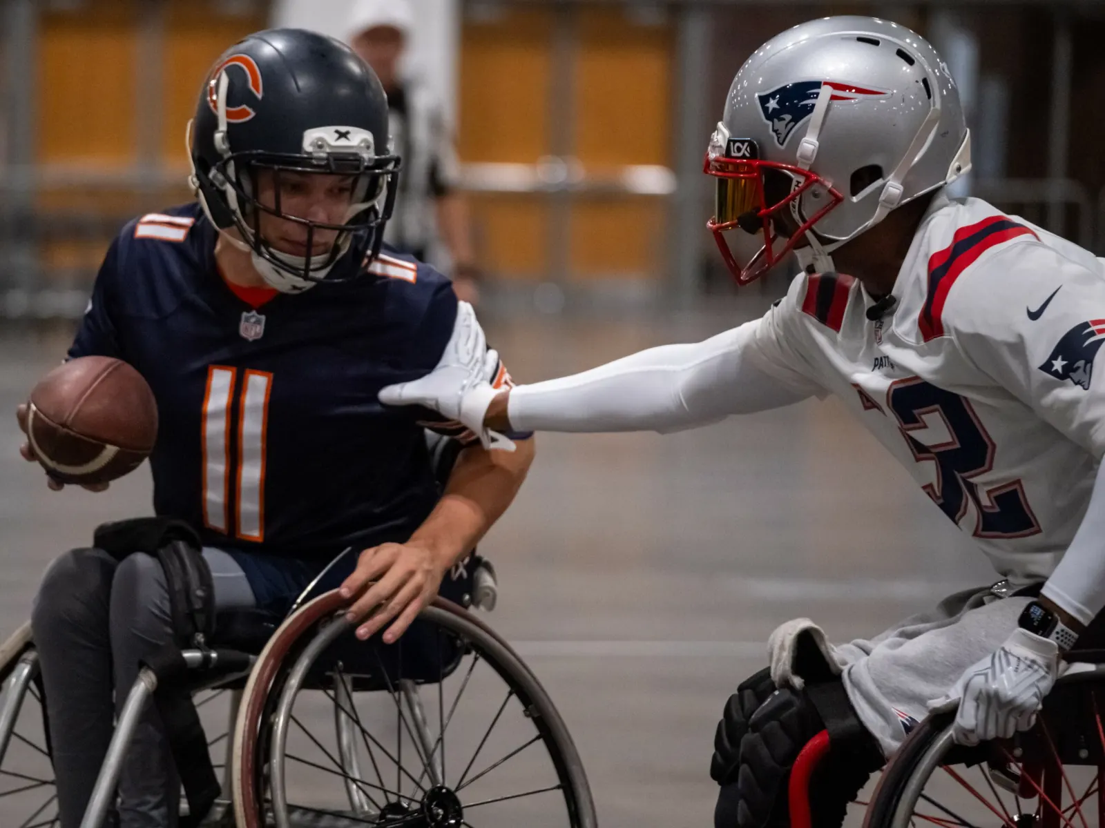 A Patriots defender reaches across to strip at the ball held by a Chicago Bears number 11 ballcarrier.