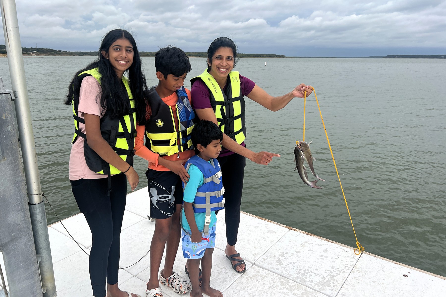 A family in life jackets shows their catch from the Lake Grapevine dock.