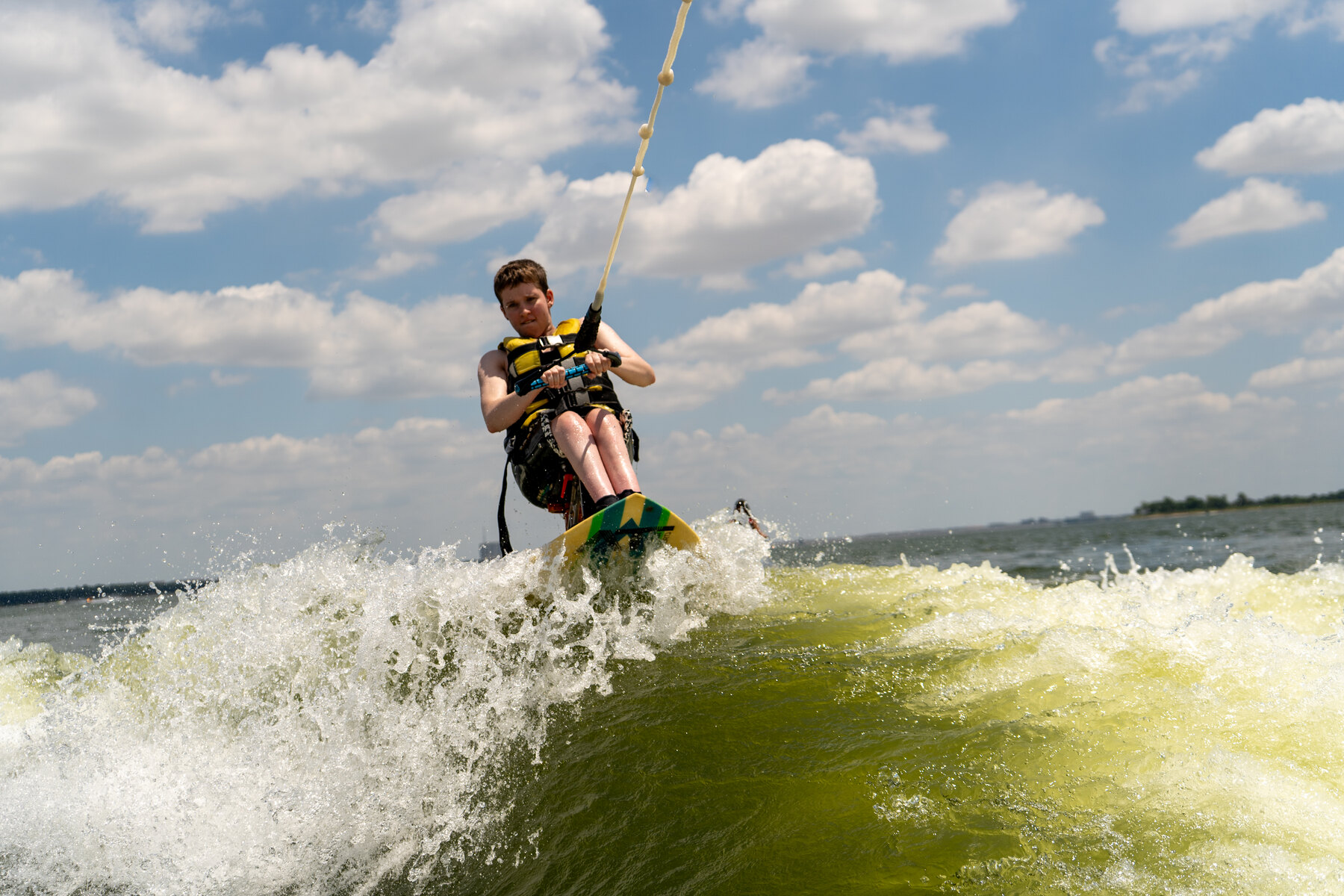 An adaptive athlete holds the tow rope while riding a seated wakeboard across Lake Grapevine.