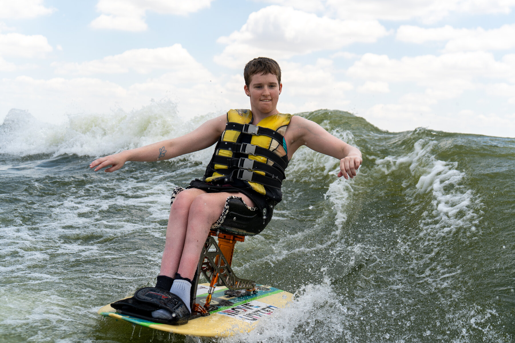 An adaptive athlete rides a seated board through the wake on Lake Grapevine.